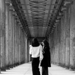 Talks - Two people walking down a long hallway with columns